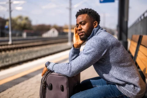 Jeune homme pensivement assis à une table, le visage appuyé sur sa main, illustrant la réflexion et les dilemmes de la jeunesse.