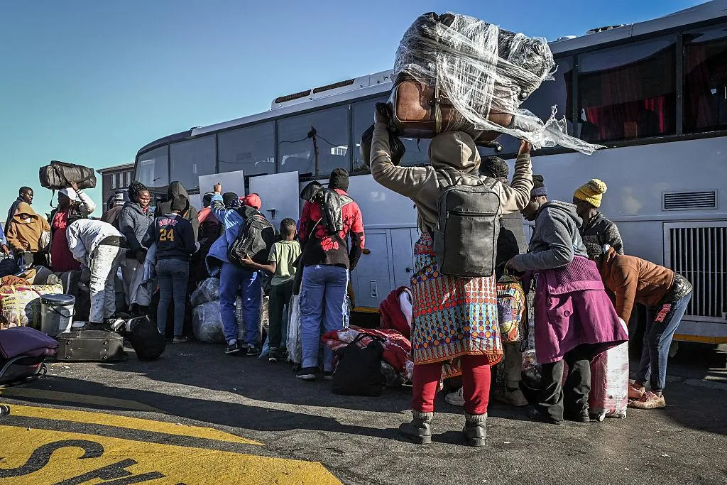 Groupe de migrants en déplacement portant des sacs et des effets personnels.